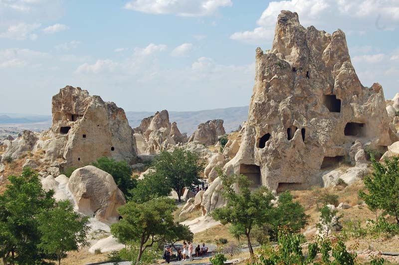 Natural stone towers dotted with man-made hollows rise above scattered trees