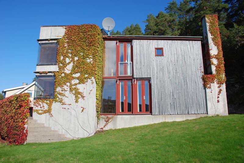 A small building with international-style properties displays a mixture of concrete and wood elements 