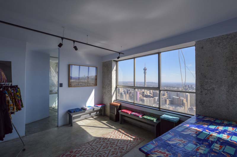 simple white room with concrete floor and wall with large window with city view