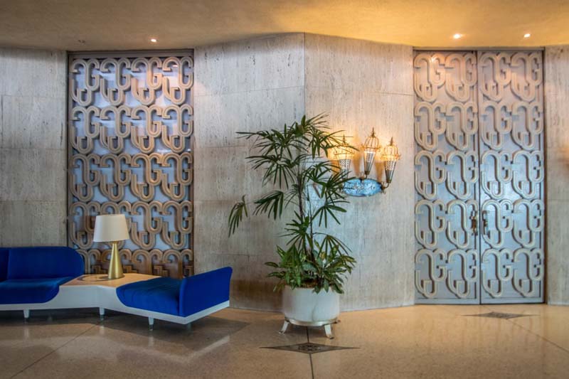 a lobby with a blue and white modernist bench and patterned doors and wall panels 